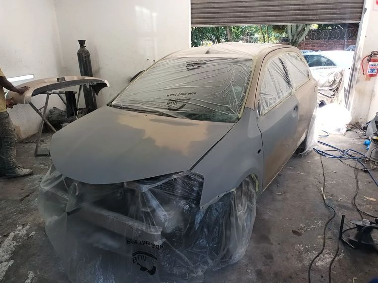 The same Etios in grey primer, masked inside the workshop